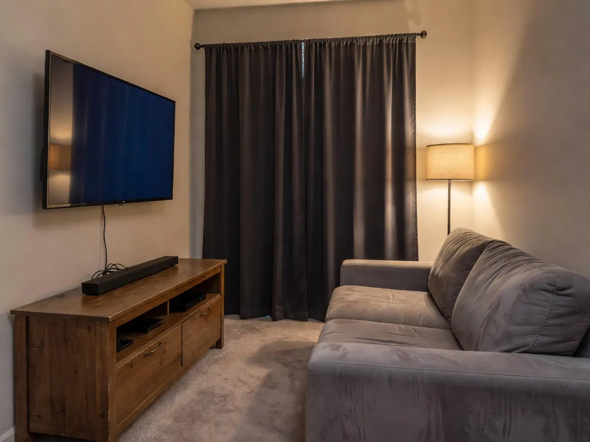 Uma sala multimídia fotorrealista e compacta em apartamento, com uma TV montada na parede, um rack de TV baixo e cortinas blackout, pré-visualizada com IA